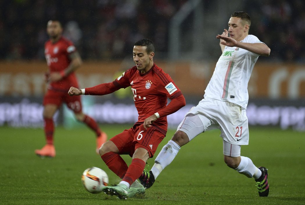 Fotbalista Bayernu Mnichov Thiago v souboji s hráčem Augsburgu Dominikem Kohrem