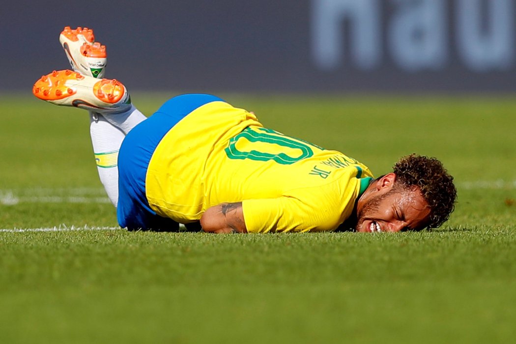 Neymar se kácí na zem po jednom z ostrých faulů Rakušanů