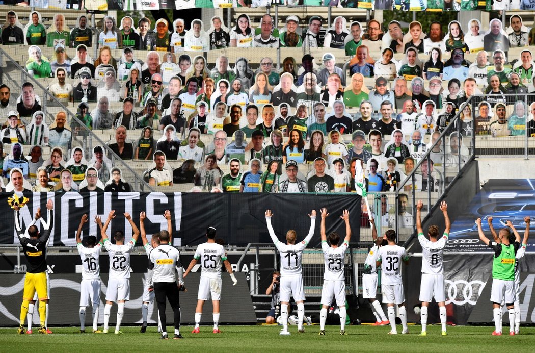 Fotbalisté Mönchengladbachu slaví vítězství nad Union Berlín před tribunou zaplněnou fotkami fanoušků