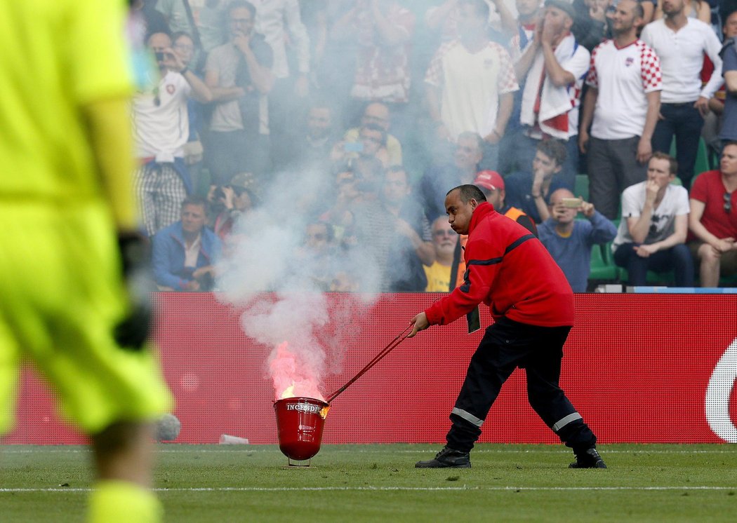 Pořadatelská služby odklízí z trávníku stadionu pyrotechniku, kterou naházeli na hřiště chorvatští fanoušci
