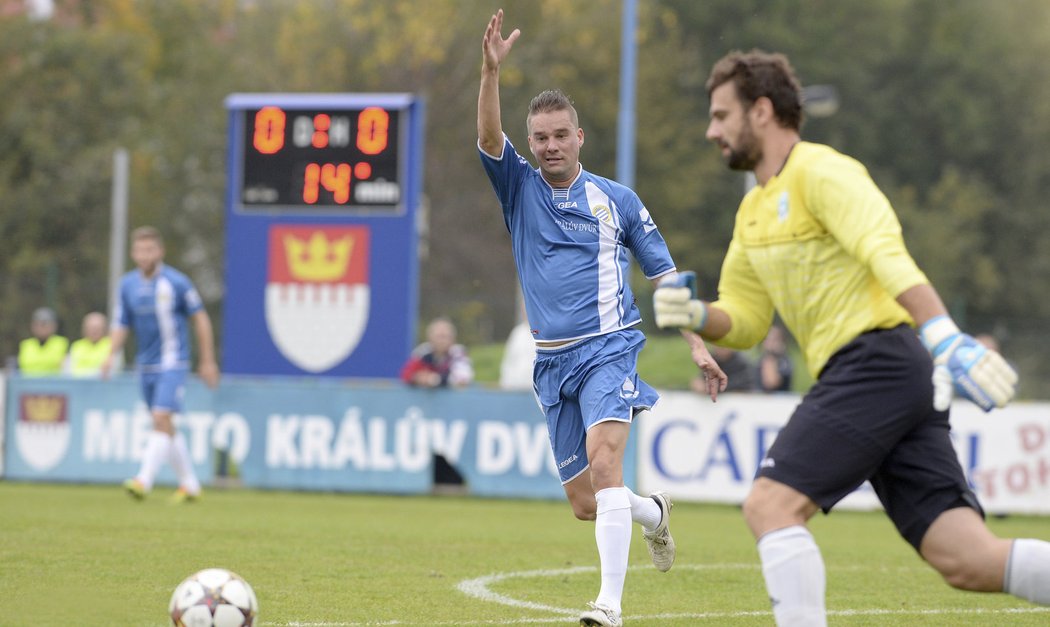 Gólman Vltavínu Ladislav Čaba odehrává míč, útočník Petr Švancara v dresu Králova Dvora se jej snaží rozhodit.