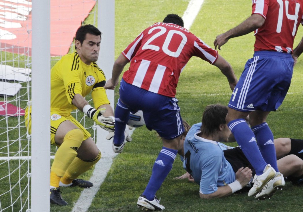 Paraguayský gólman Justo Villar a Nestor Ortigoza se snaží odvrátit míč od branky, zatímco Sebastian Coates leží na zemi