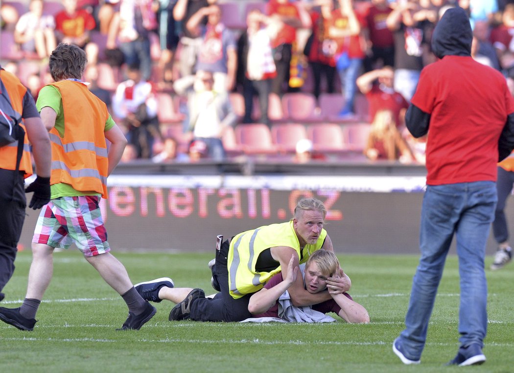 Sparťanský pořadatel pacifikuje jednoho z fanoušků, kteří po prohraném derby vtrhli na hrací plochu