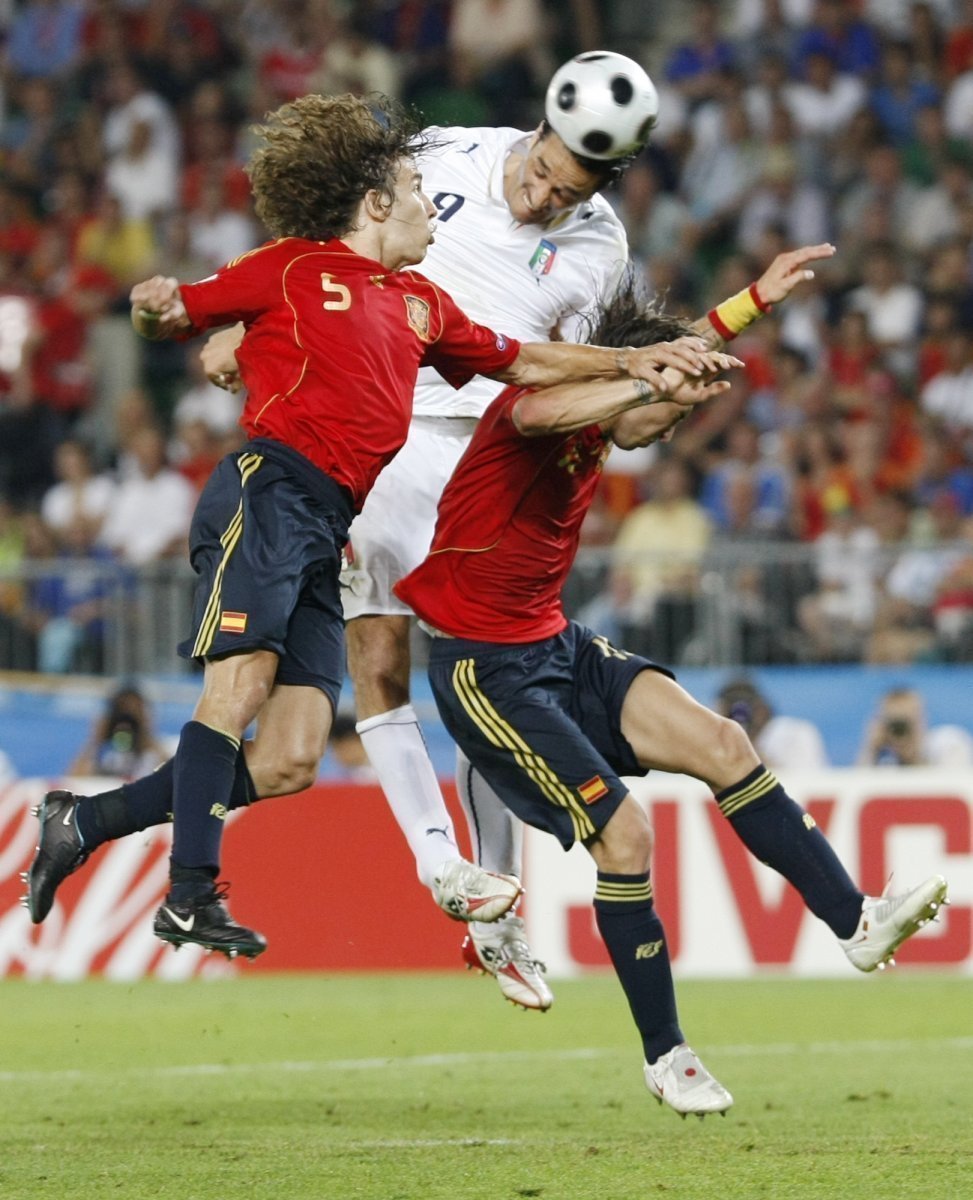 Italský útočník Luca Toni hlavičkuje v obležení Španělů Puyola a Ramose (vpravo).