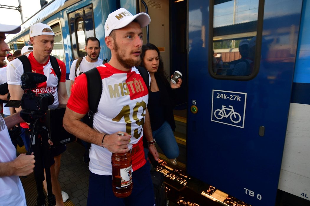 Obránce Slavie Vladimír Coufal s lahví rumu nastupuje do vlaku v Ostravě