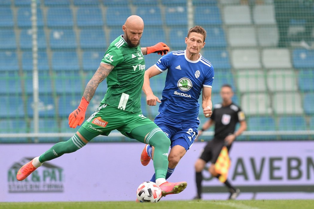 Olomoucký brankář Matúš Macík odkopává míč před dotírajícím Milanem Škodou