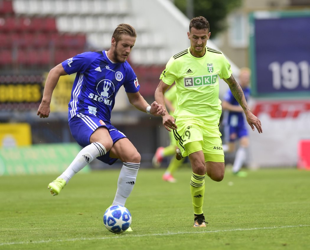 Olomoucký Jakub Plšek drží míč v souboji s Vukadinem Vukadinovičem z Karviné