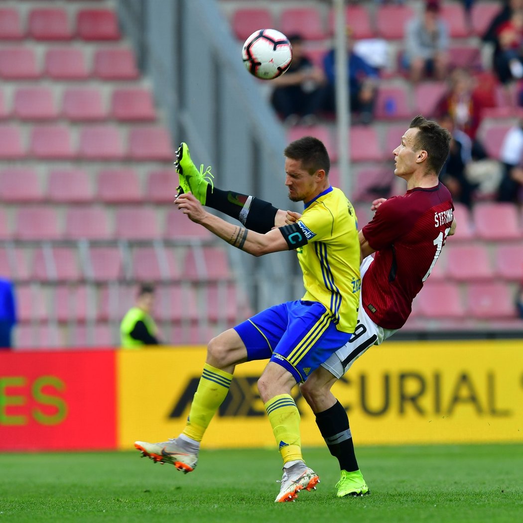 Sparťan Lukáš Štetina odkopává míč před dotírajícím kapitánem Zlína Lukášem Železníkem