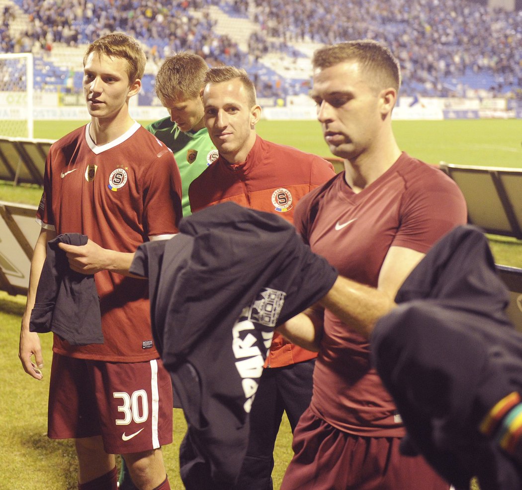 Fotbalisté Sparty si po zápase na Baníku oblékají trička od fanoušků, vlevo je střelec vyrovnávacího gólu Lukáš Juliš