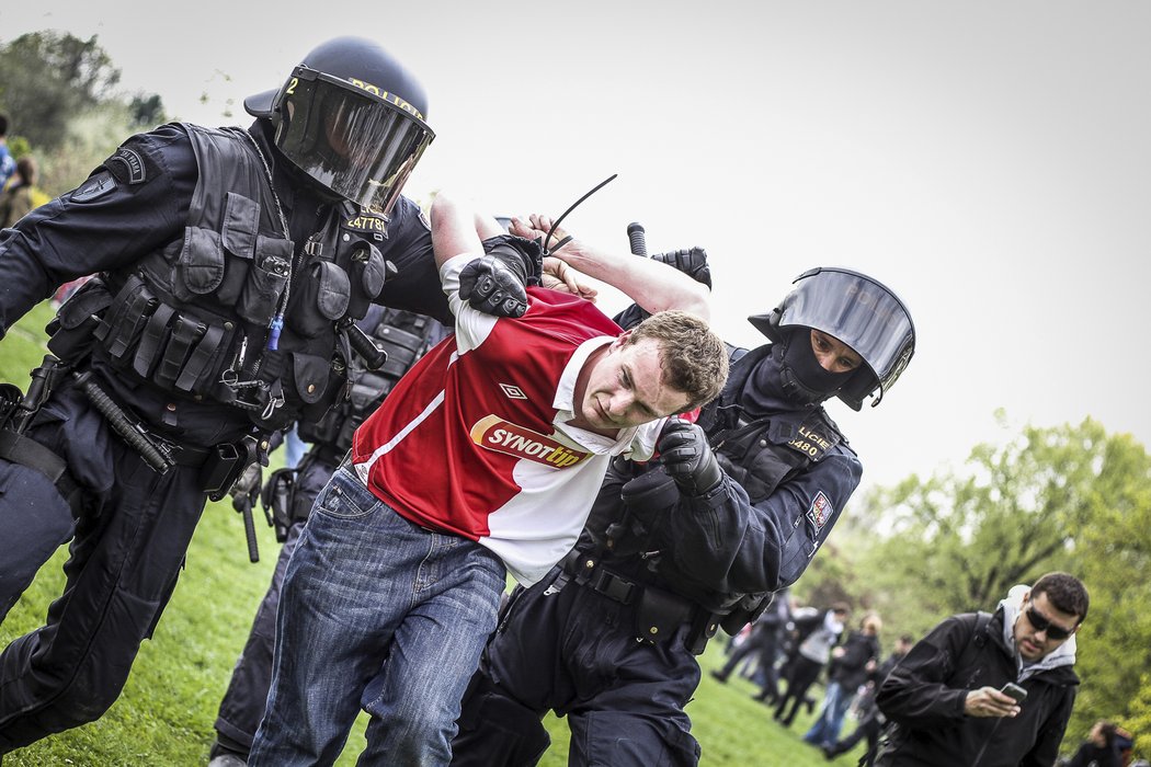 Policisté odvádějí jednoho z fanoušků Slavie v poutech