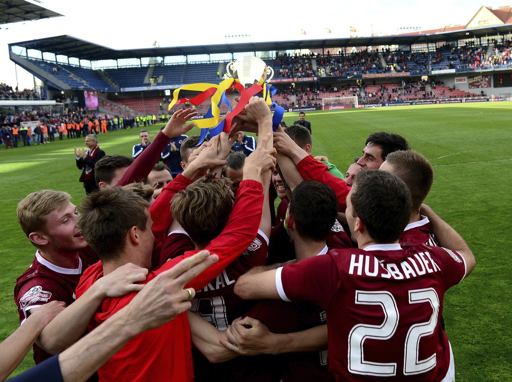 Klubko sparťanských fotbalistů si užívá oslav s fanoušky po výhře nad Olomoucí, nad hlavami drží repliku poháru, kterou jim před fanoušky předal masér Stránský