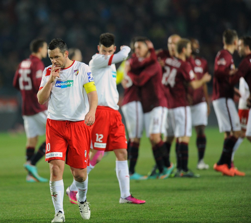 Zklamaní fotbalisté Plzně Pavel Horváht a Michal Ďuriš odcházejí ze hřiště, zatímco za nimi se radují sparťané z výhry