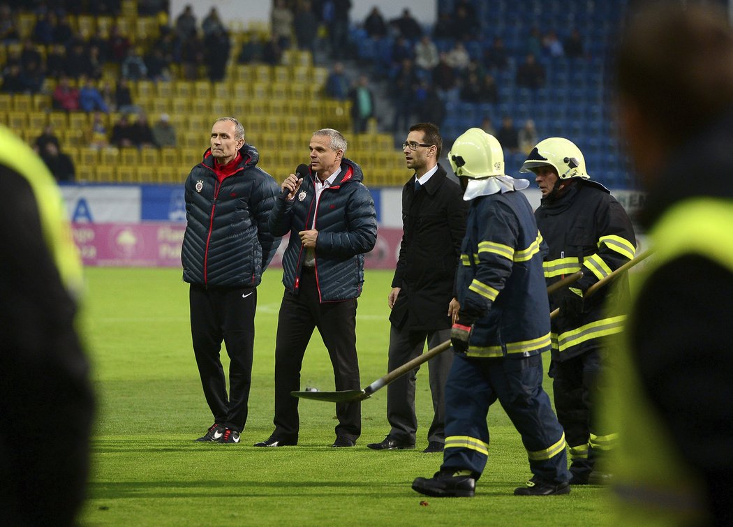 Hasiči odnášejí dýmovnici, kterou fanoušci Sparty vrhli po vlastním trenérovi Vítězslavu Lavičkovi