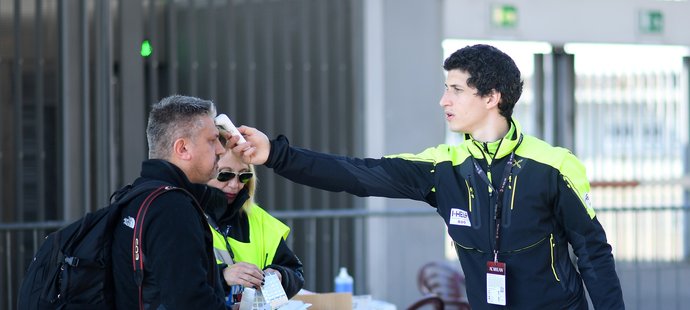 Jeden z pořadatelů měří teplotu fotografovi před vstupem na stadion před zápasem AC Milán - Janov