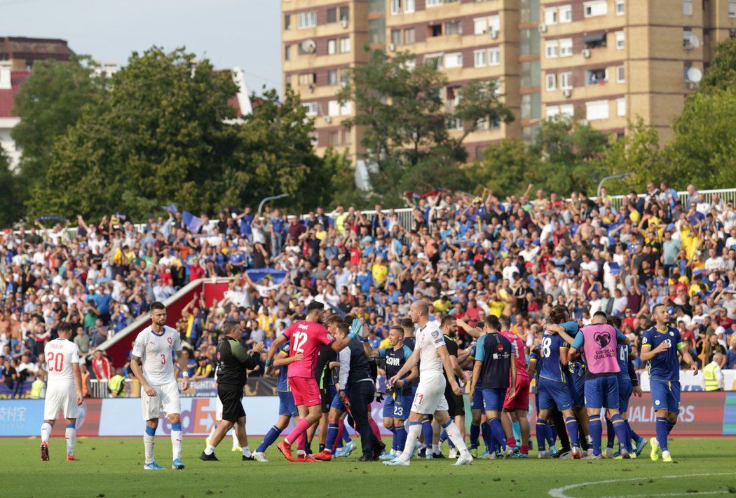 Zklamaní čeští fotbalisté po prohře v Kosovu, jehož hráči se v pozadí radují z výhry 2:1