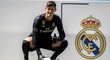 Thibaut Courtois pózuje pro média vedle znaku Realu Madrid