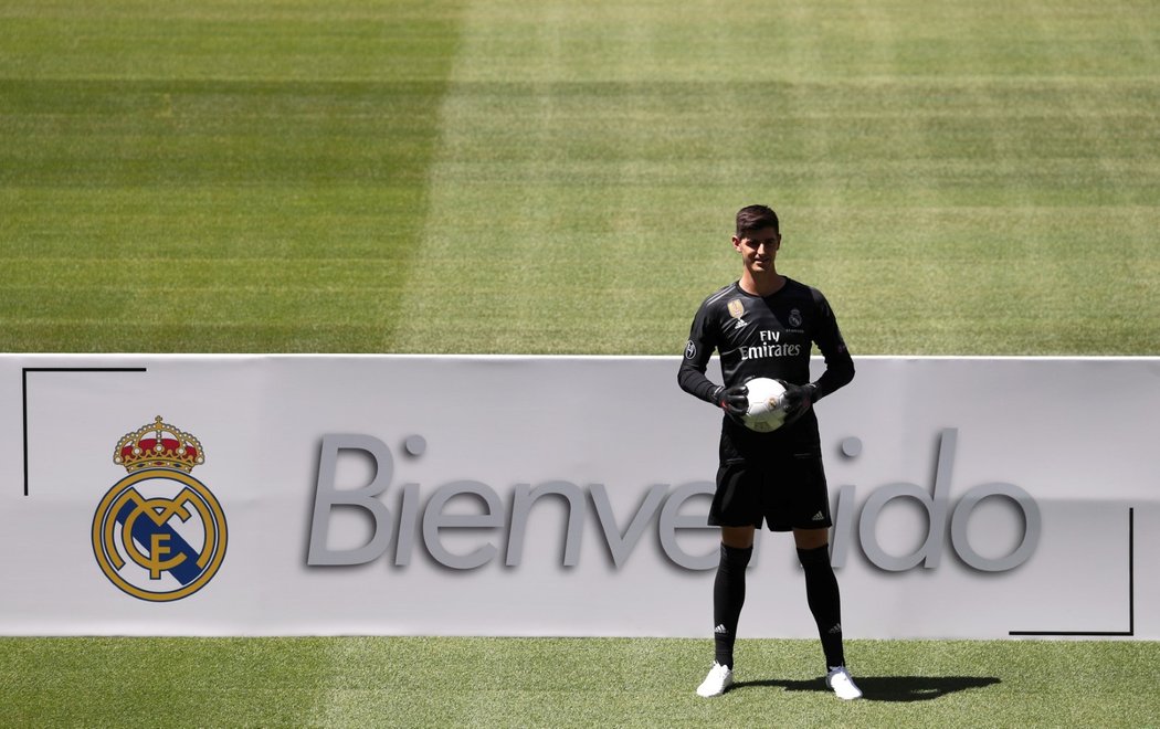 Thibaut Courtois pózuje pro média vedle znaku Realu Madrid