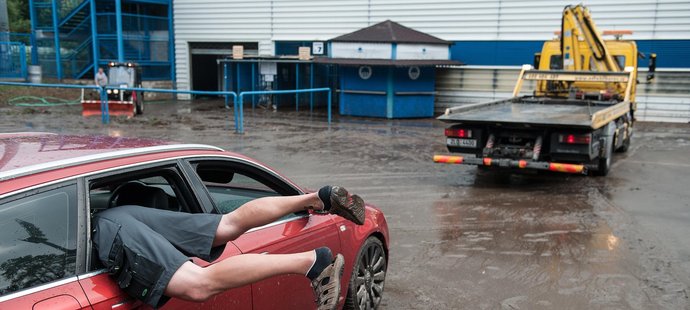 Na snímku je pracovník odtahové služby hledající v zaplaveném automobilu oko k zachycení lana