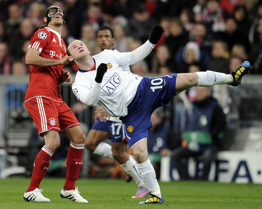 Wayne Rooney (vpravo) číhá na vysoký míč před bayrnským Martinem Demichelisem