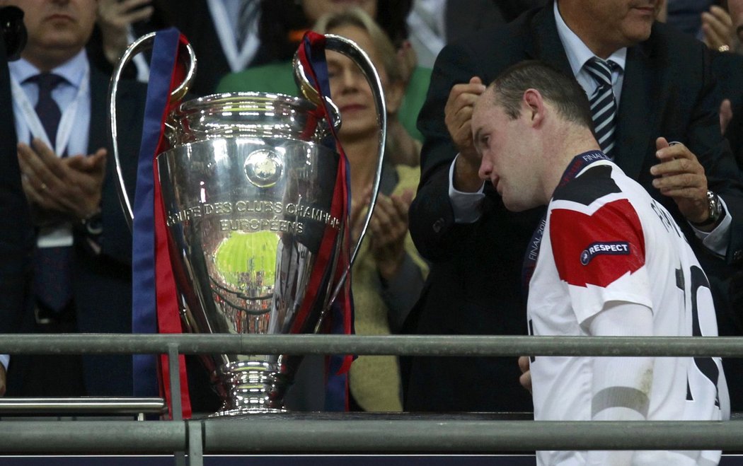 Wayne Rooney prochází kolem poháru pro vítěze Ligy mistrů, který ovšem patří Barceloně