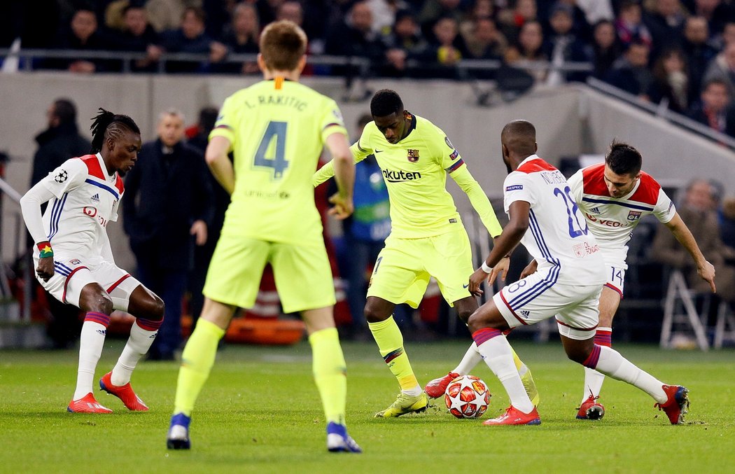 Barcelonský Ousmane Dembele se snaží projít mezi bránícími hráči Lyonu v zápase osmifinále Ligy mistrů