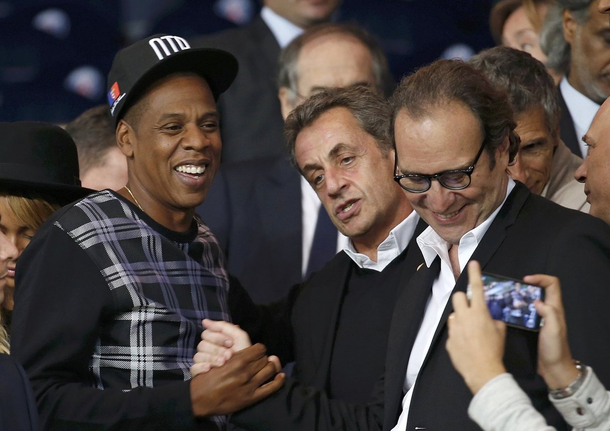 Rapper Jay-Z se zdraví s bývalým francouzským prezidentem Sarkozym v hledišti zápasu PSG - Barcelona