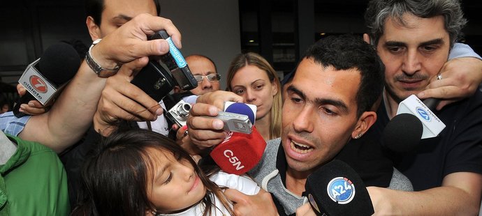 Carlos Tévez drží svoji dceru Florencii, zatímco odpovídá na dotazy novinářů na letišti v Buenos Aires