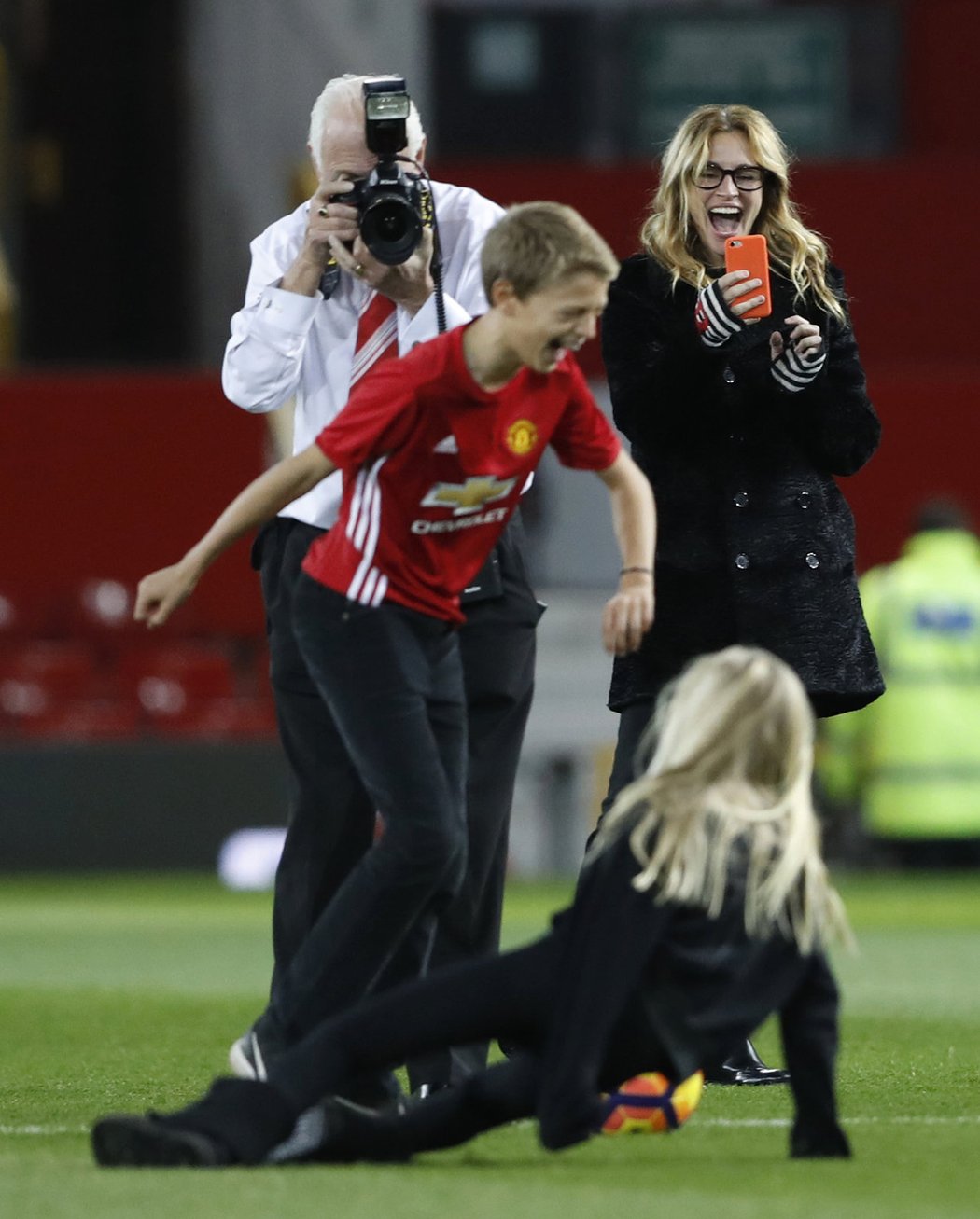 Herečka Julia Roberts, která se považuje za fotbalovou mámu, natáčí na Old Trafford svou dceru, jež skluzem sestřelila další z dětí pohybujících se po trávníku