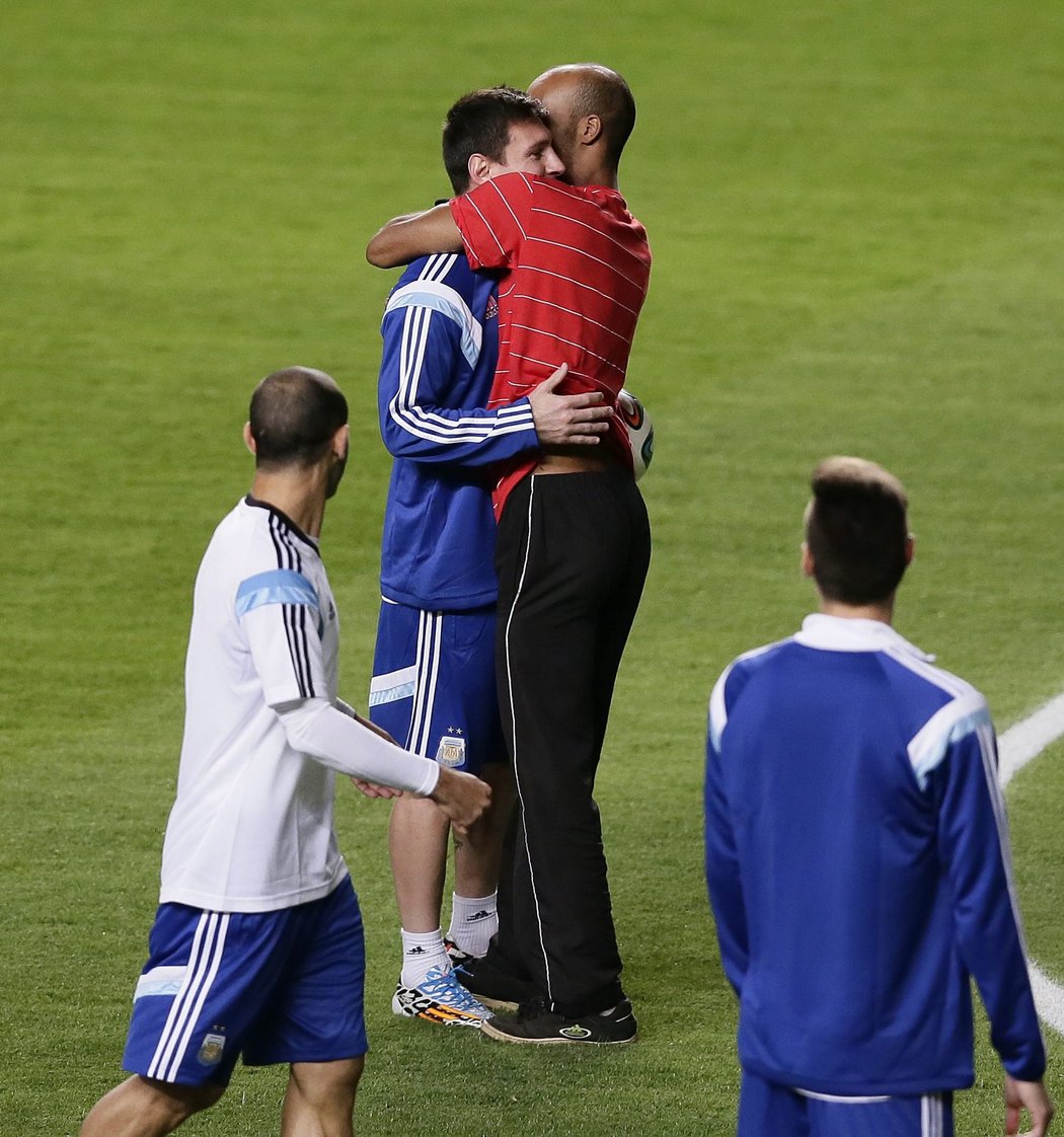 Jeden z fanoušků, kteří pronikli na hřiště po argentinském tréninku, se objímá s Lionelem Messim