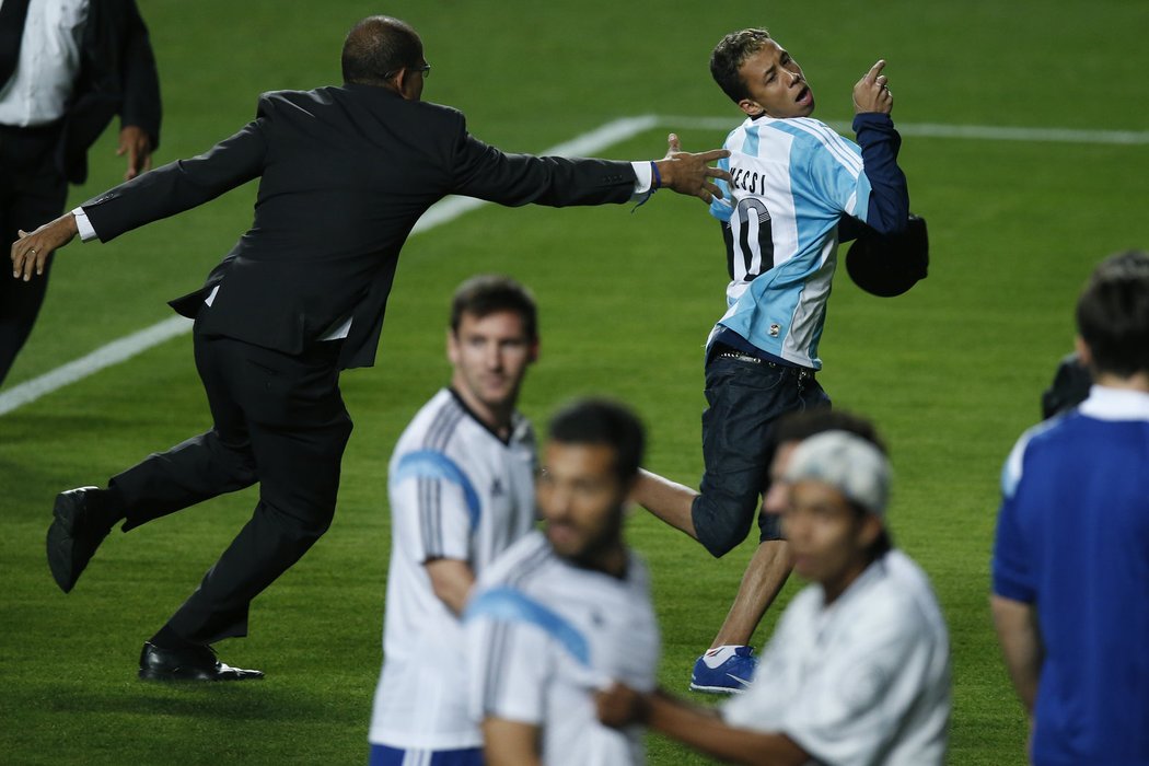 Ochranka se snaží odchytit jednoho z fanoušků, kteří vtrhli na hřiště po tréninku Argentinců a vrhli se především na Lionela Messiho