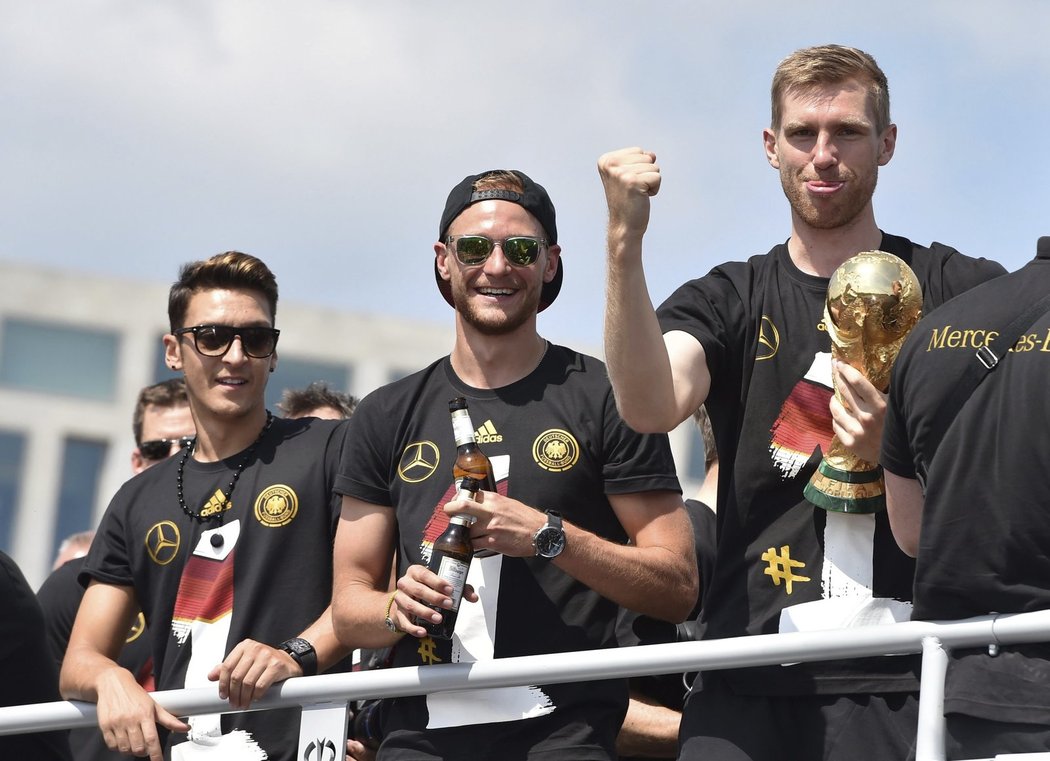 Mesut Özil, Benedikt Höwedes a Per Mertesacker při triumfální jízdě mistrů světa Berlínem