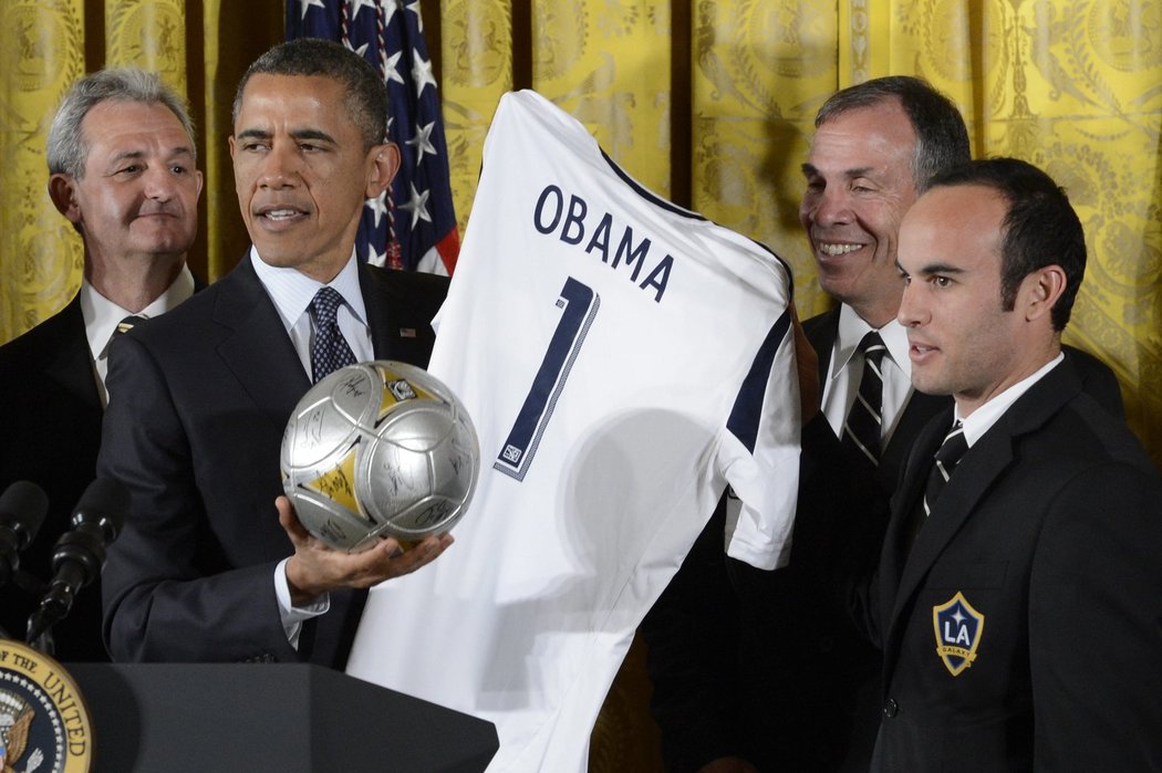 Barack Obama pózuje s dárky od fotbalistů LA Galaxy, vpravo je kapitán týmu Landon Donovan, vedle kouč Bruce Arena