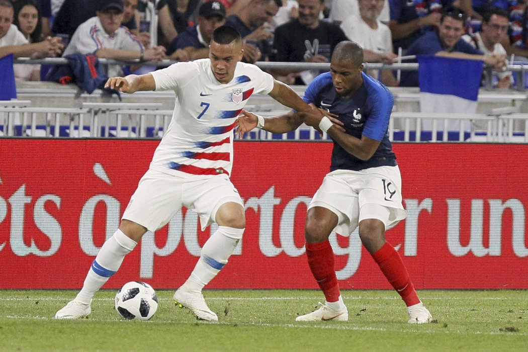 Djibril Sidibe z Francie se snaží sebrat míč Bobbymu Woodovi z USA