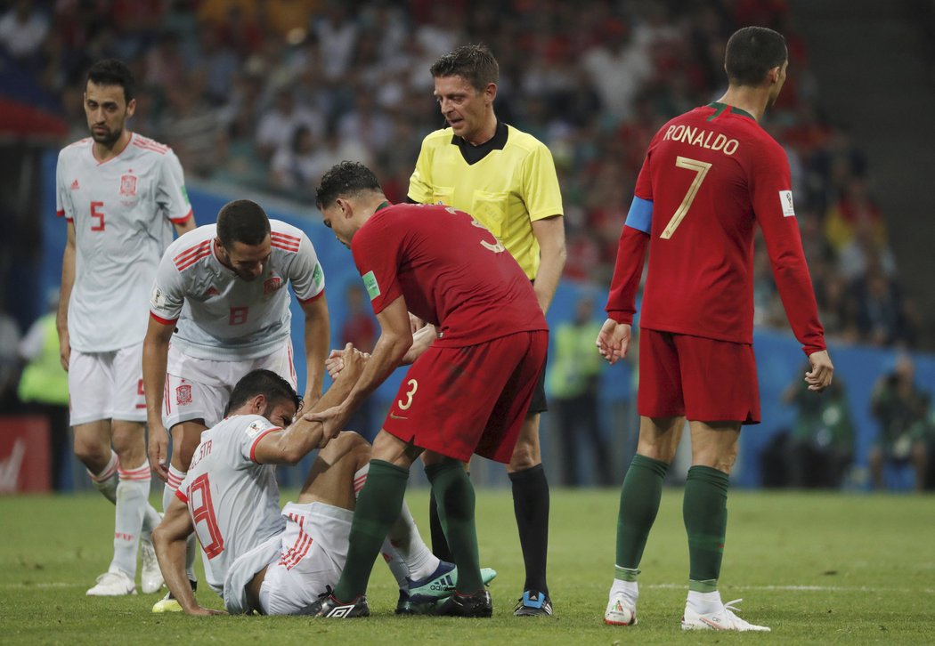 Španěl Diego Costa se těžko zvedá po jednom souboji, pomáhá mu i Portugalec Pepe