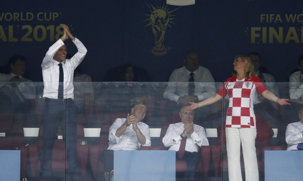 Chorvatská prezidentka Kolinda Grabarová-Kitarovičová gestikuluje na Emmanuela Macrona, který se raduje ve finále MS. Mezi nimi Vladimir Putin a šéf FIFA Infantino