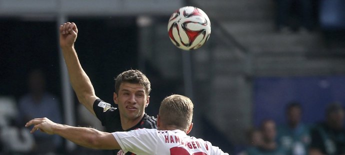 Thomas Müller, jedna z hvězd Bayernu Mnichov ve vzdušném souboji s Matthiasem Ostrzolekem z Hamburku v utkání bundesligy.