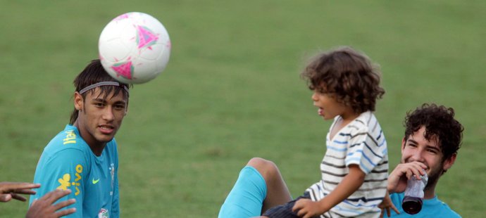 Brazilci Neymar (vlevo) a Alexandre Pato pozorují hrajícího si Enza - syna jejich spoluhráče Marcela