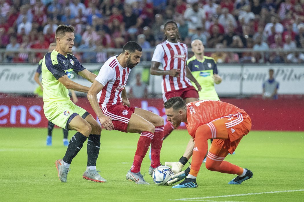 Gólman Olympiakosu Pireus likviduje míč před plzeňským Lukášem Kalvachem