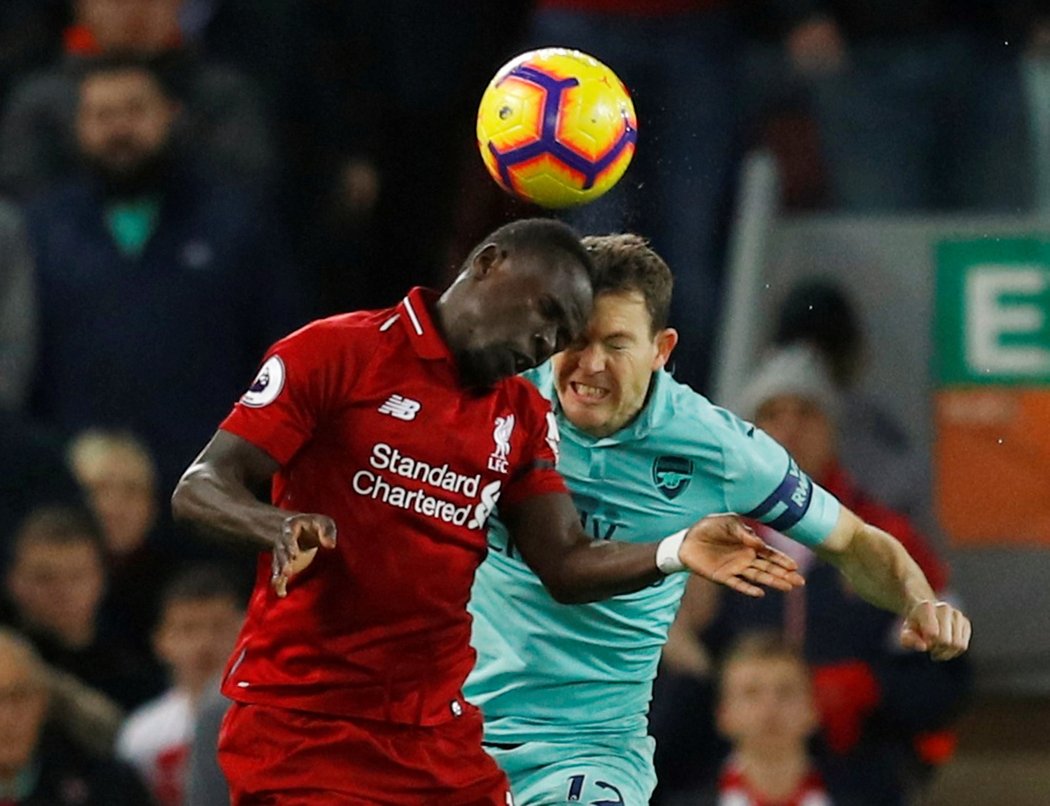 Hlavičkový souboj liverpoolského Sadia Maného s Stephanem Lichsteinerem z Arsenalu