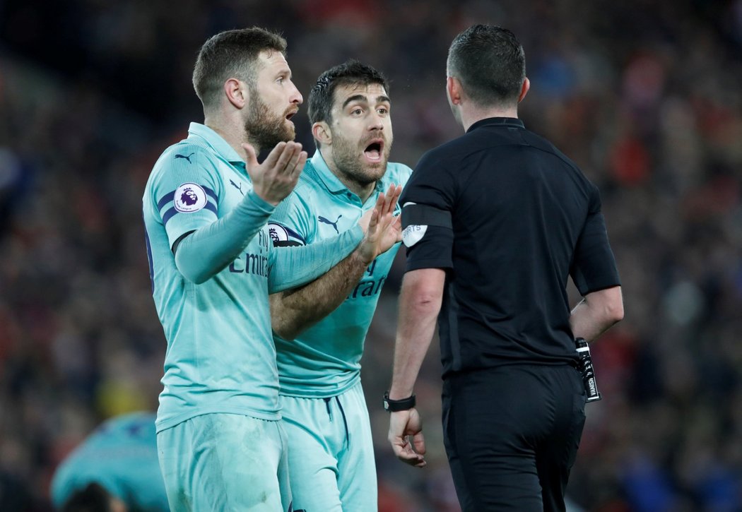 Sokratis Papastathopoulos a Shkodran Mustafi protestují proti rozhodnutí rozhodčího Michaela Olivera, který odpískal penaltu pro Liverpool po faulu na Salaha