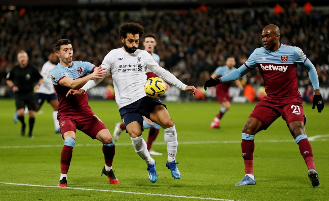 Liverpoolský Mohamed Salah si kryje míč před dotírajícími hráči West Hamu.