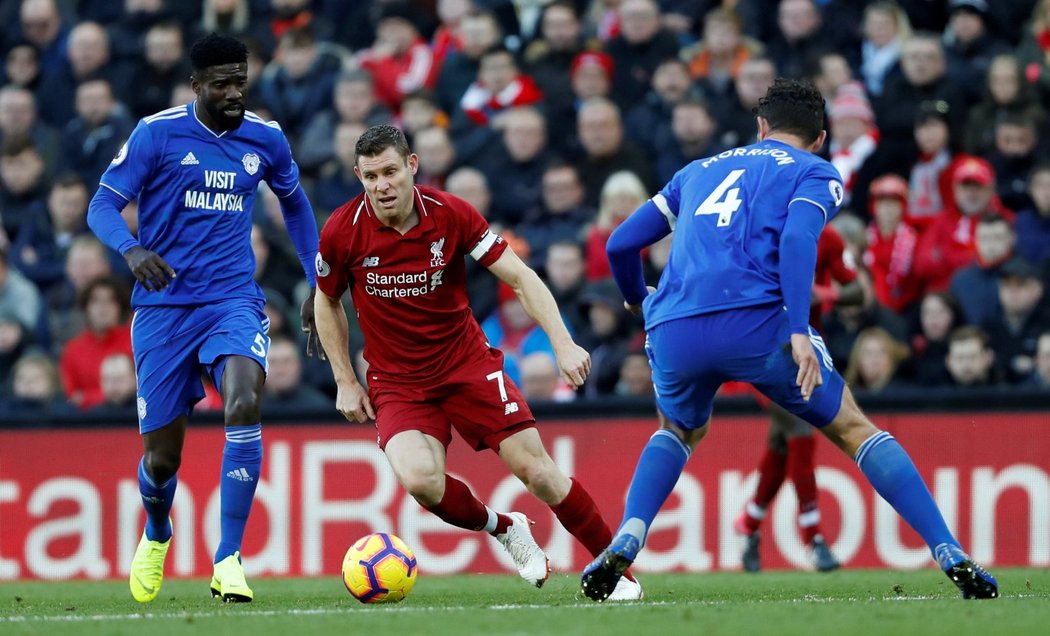 Liverpoolský James Milner prochází mezi dvojicí bránících hráčů Cardiffu