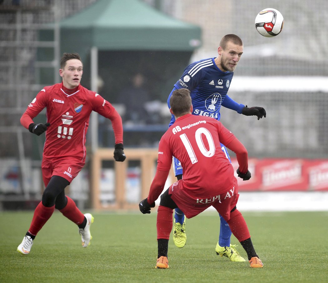 Olomoucký Martin Šindelář hlavičku v zápase s Baníkem, sledují ho Dyjan Carlos De Azevedo (vlevo) a Jan Matěj