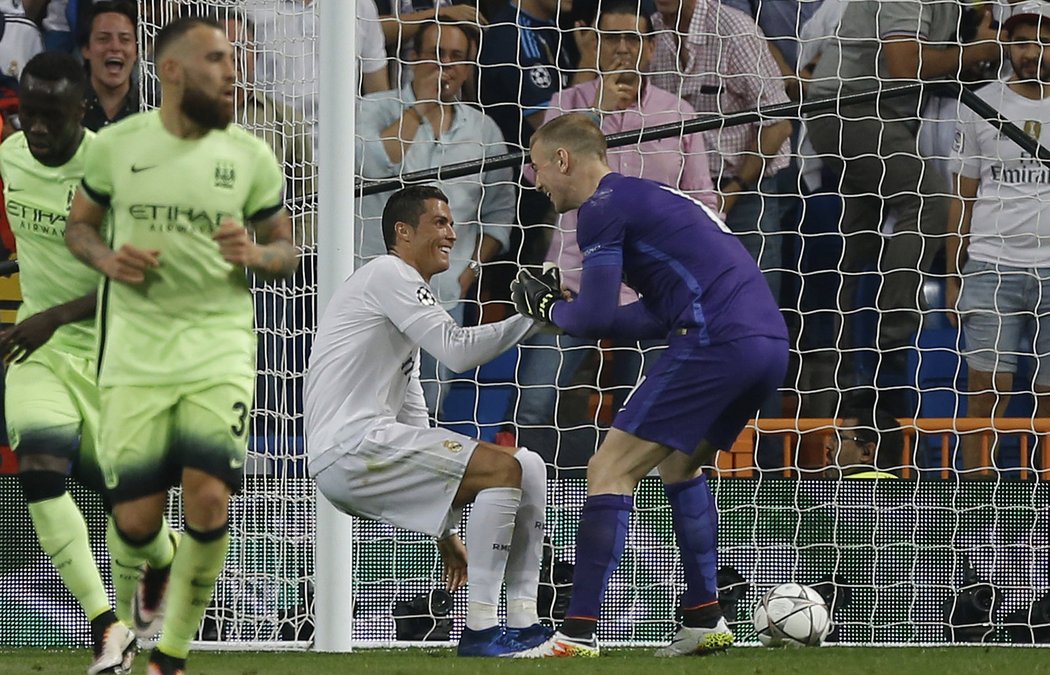  Joe Hart pomáhá na nohy Ronaldovi. Oba celou situaci přešli úsměvem