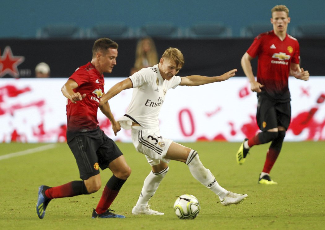 Martin Ödegaard v souboji s Anderem Herrerou z Manchesteru United.