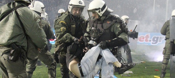 Řečtí policisté odnášejí jednoho z agresivních fanoušků, kteří narušili pohárový zápas mezi PAOK Soluň a Olympiakosem Pireus