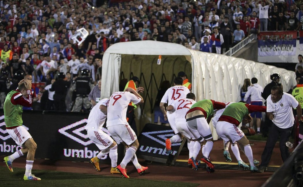 Albánští fotbalisté se kryjí před sprchou nejrůznějších předmětů, které na ně létají od srbských fanoušků
