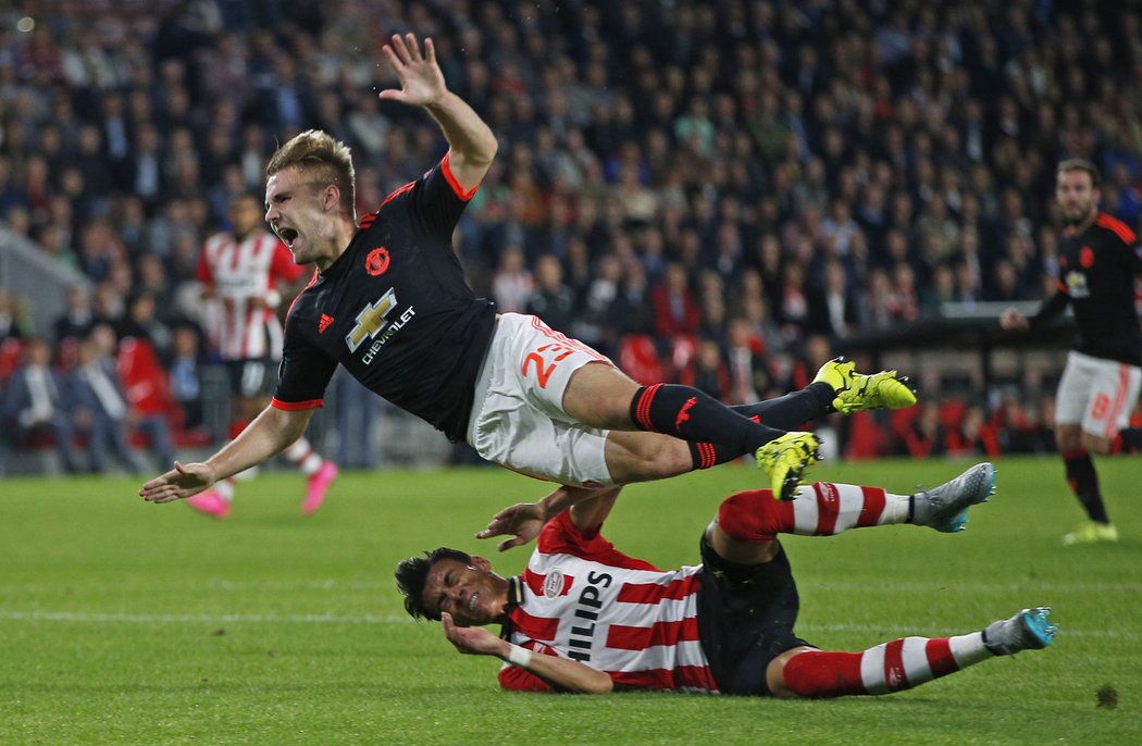 Luka Shaw z Manchesteru United padá po souboji s Hectorem Morenem z PSV