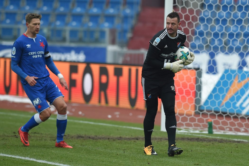 Gólman Baníku Ostrava Jan Laštůvka kryje míč před kapitánem Slavie Milanem Škodou