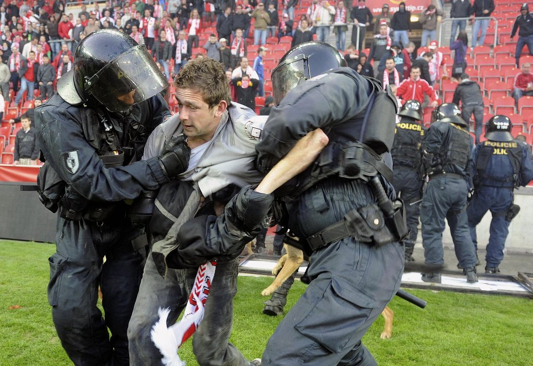 Slávistické řádění v Edenu: Policisté odvádějí jednoho z fanoušků, kteří o poločasu obsadili hřiště a pokusili se napadnout členy klubového managementu. Pustili se také do šarvátek s policisty, kteří proti nim zakročili.